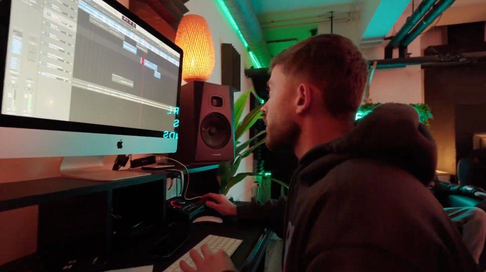 Mentor at the mixing desk — Logic Pro session, monitors, warm studio lighting